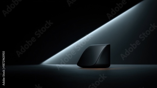 A sleek black device illuminated by a dramatic light beam in a minimalist dark setting
