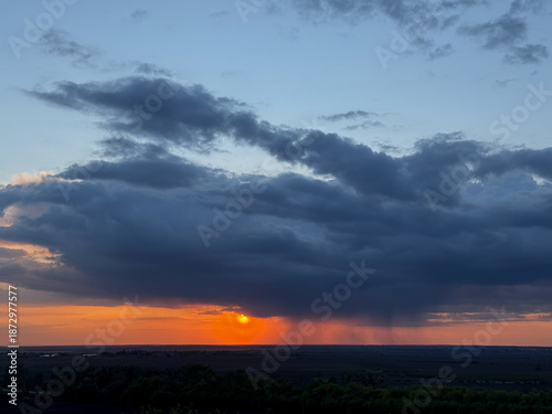 Obraz na płótnie Sunset creating orange glow under rain clouds