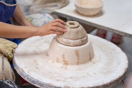 Potter Shaping Clay Bowl by Hand on Spinning Wheel in Traditional Ceramic Workshop