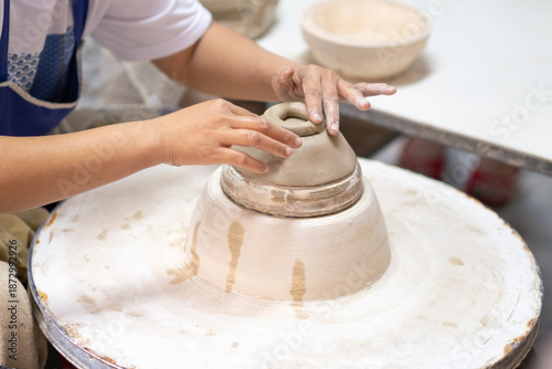 Close-Up of Artisan Hands Refining Ceramic Bowl Shape on Pottery Wheel During Production