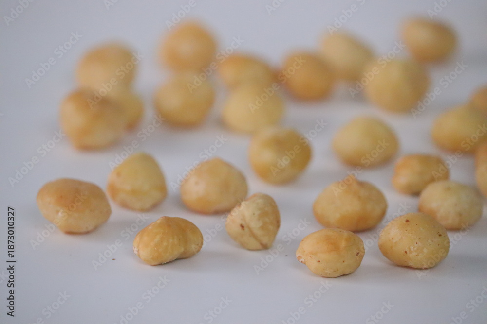 Fototapeta premium Roasted macadamia nuts presented in a rustic close-up scatter, featuring whole shelled kernels