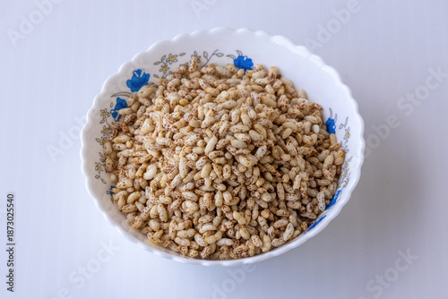 Obraz na płótnie Close-up of crunchy puffed brown rice served in a white ceramic bowl against a white backdrop