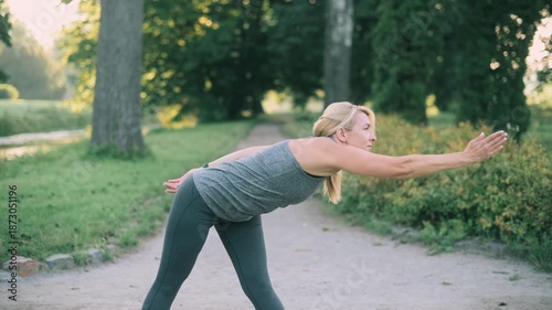 A middle-aged woman warms up before a morning workout in the park.