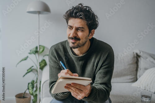 Handsome middle eastern looking man journaling or writing in a notebook