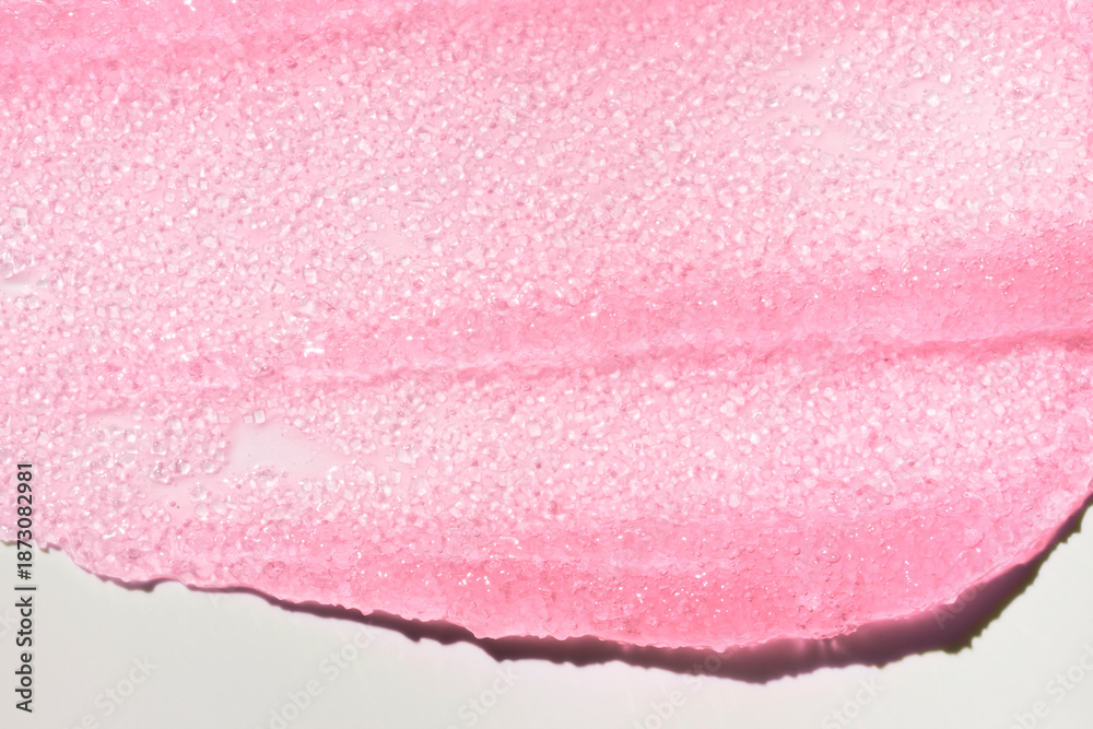 Fototapeta premium Macro texture of shimmering pink lip gloss. Beauty product sample swatch with sparkling particles and glossy finish, isolated on white background