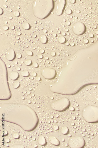 Cosmetic moisturizing liquid drops on nude skin color beige pastel background. Toner or lotion. Hyaluronic serum