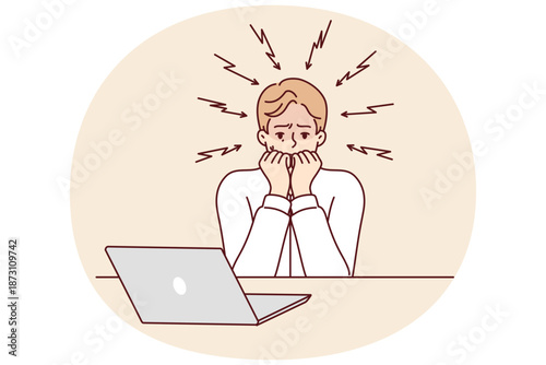 Frightened man bites nails after reading news on laptop about approaching unemployment or recession crisis. Frightened guy suffered from online bullying and received email written in hate language
