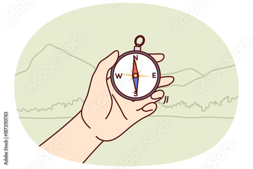 Compos in hand of person went on hike and determines direction of world to find way and navigate terrain. Traveling through national park and using compos to avoid getting lost and find your way back