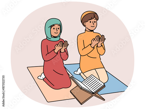 Little islamic children pray sitting on knees near holy quran studying in muslim school. Islamic kids from mosque learn to observe national cultural traditions during month of ramadan