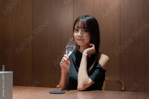 バーでシャンパンを飲む黒いドレスを着た笑顔の日本人女性モデル