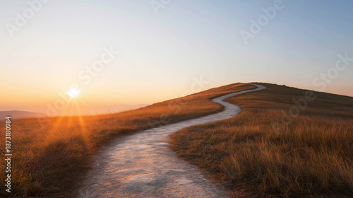 Desolate winding path climbing up a green hill at sunrise, symbolizing the ideas of obstacles, potential, and liberation