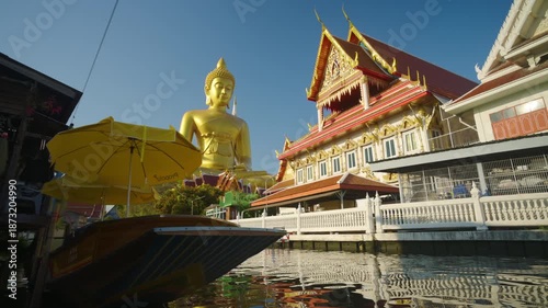 Giant golden buddha statue at the Wat Paknam Phasi Charoen temple with wooden boat famous buddhist and the peaceful beauty in Bangkok, Thailand
