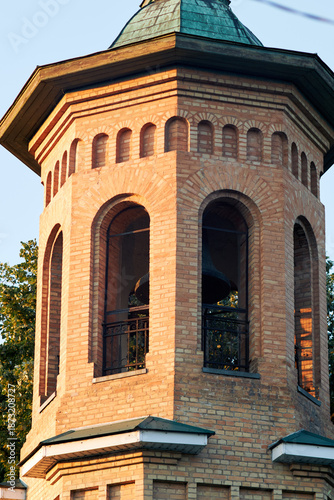 Historic brick bell tower with arched windows illuminated by warm golden hour light