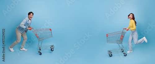 Shopping lifestyle concept with Asian couple pushing shopping carts playful retail experience joyful consumerism supermarket fun sale promotion happiness modern spending culture.
