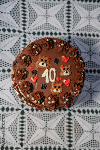 Wallpaper Mural Rich chocolate cake with piped buttercream, teddy bear motifs, hearts, and a bold number ten, displayed on a lace-covered table as a festive celebration centerpiece Torontodigital.ca