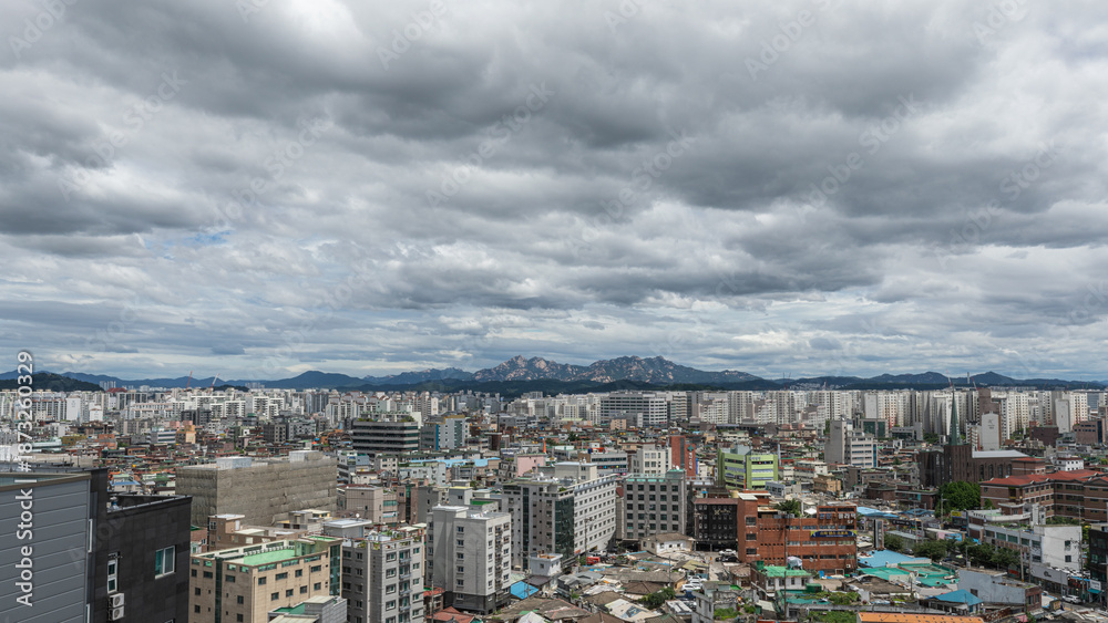 Naklejka premium Dense residential apartment district under a dramatic cloudy sky with mountain view