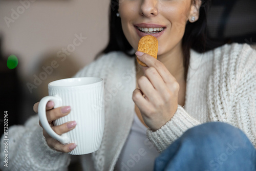 Fotografía A woman enjoys her cookie alongside coffee, radiating joy and cozy vibes in a home setting