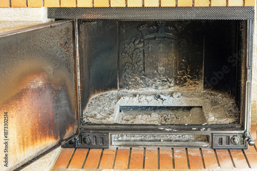 Ashes and soot fill the empty fireplace area