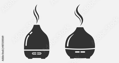 A pair of dark gray essential oil diffusers emitting a gentle mist, placed on a clean white background, viewed from the front