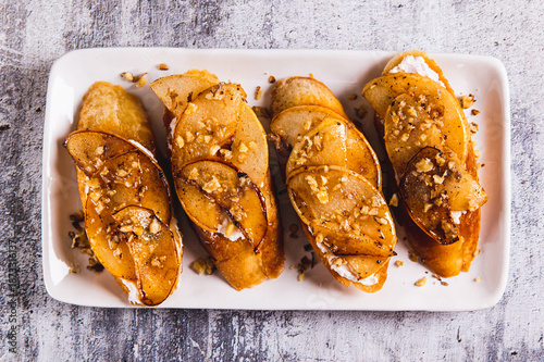 Foto Close up of sweet sandwiches with ricotta, baked pear, honey and nuts on a plate