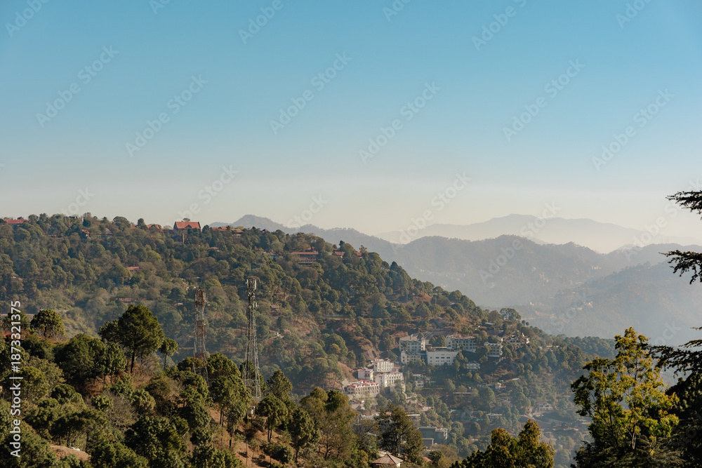 Obraz premium Mountain Serenity: A Vista of Lush Hills, Distant Peaks, and Clear Skies in a Hazy Landscape, Perfect for Travel, Nature, and Scenic Backdrop Views