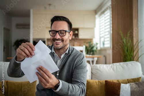 Smiling man opening mail letter with good news