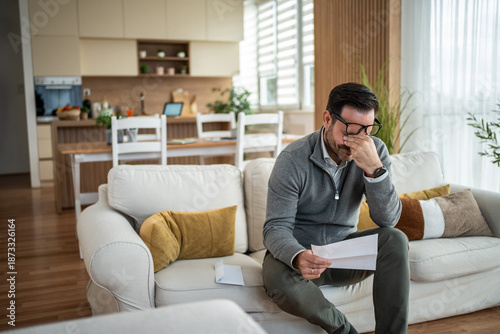 Schilderij op canvas Man experiencing financial stress reading bills at home