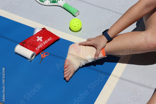 Pickleball player with a ankle injury during a match. Pickleball athlete holding the foot with pain while is in the pickeball court floor