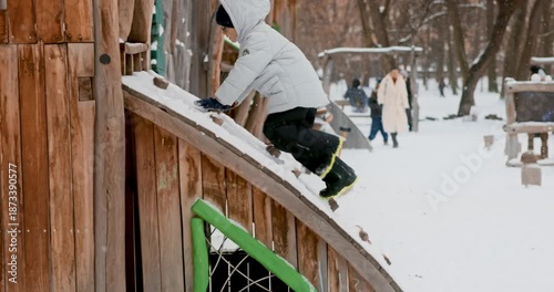 Child Playing on Snowy Playground Slide in Winter Park