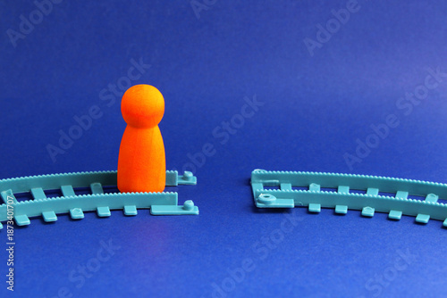 Person walking on a railway line with the path interrupted, colorful wooden figure