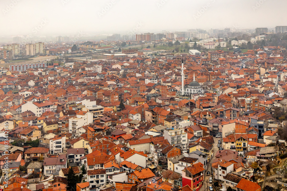 Obraz premium Aerial orange rooftop panorama of residential buildings forming a dense city center under overcast daylight conditions, Prizren, Kosovo