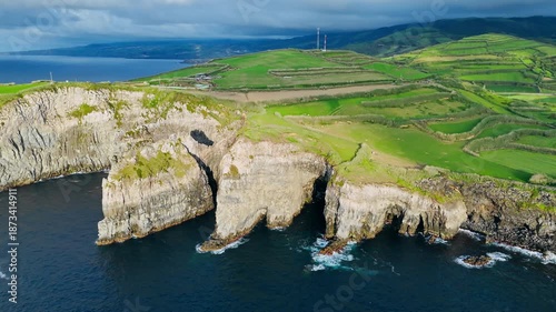 Volcanic headland with sharp rock ridges and high cliffs on the Azores coast in low evening light. Aerial view