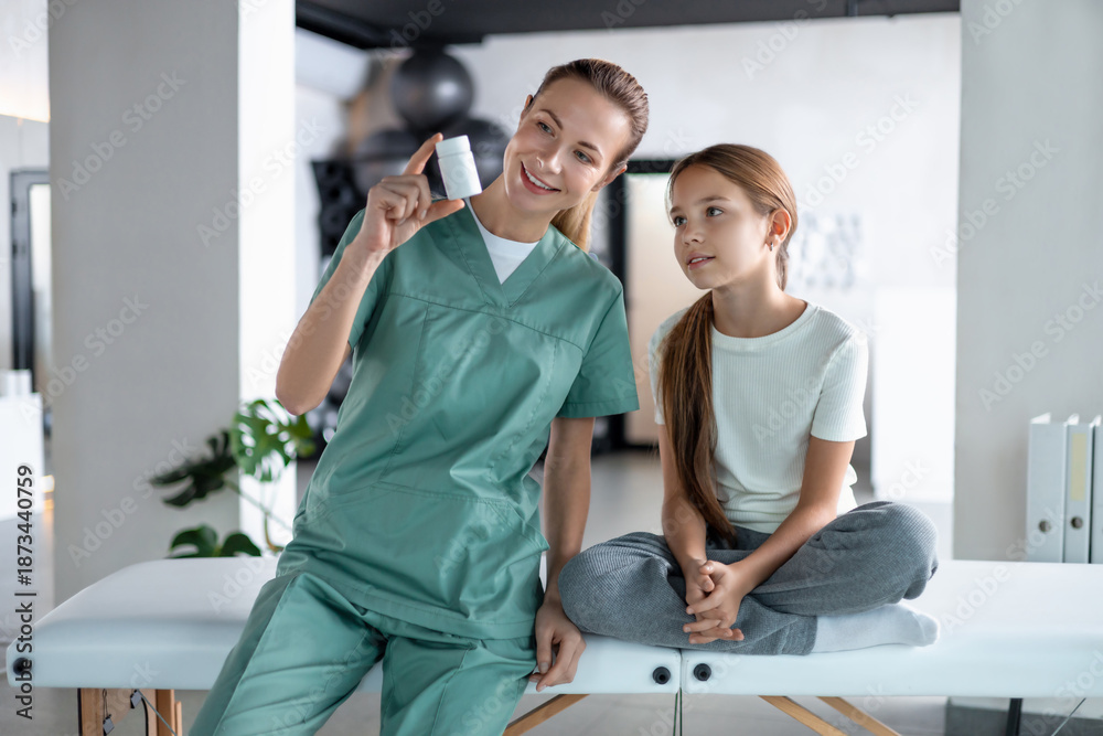 Fototapeta premium Female physiotherapist and little girl sitting communicating