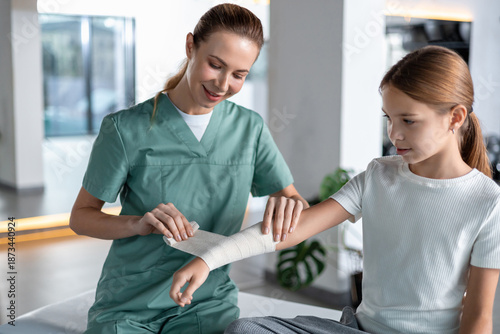 Fényképezés Nurse wrapping bandage around child’s injured arm