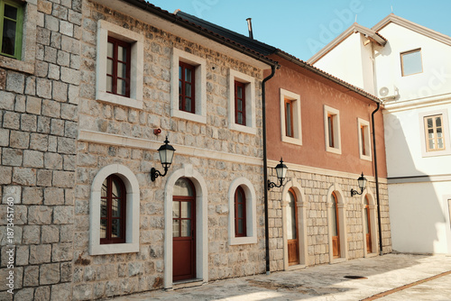 Row of stone houses with arched doors and lanterns in Andricgrad, Visegrad, Bosnia and Herzegovina. Harmonious historic street with warm afternoon light.