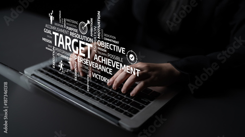 A close-up view of hands typing on a laptop with words associated with success and achievement creatively arranged around them, symbolizing motivation and focus. Tessel
