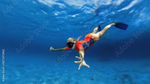 Woman wearing fins and mask swimming underwater in clear blue sea of Blue Lagoon, enjoying summer vacation exploring vibrant aquatic environment with sun rays in Drvenik Veli island of Croatia