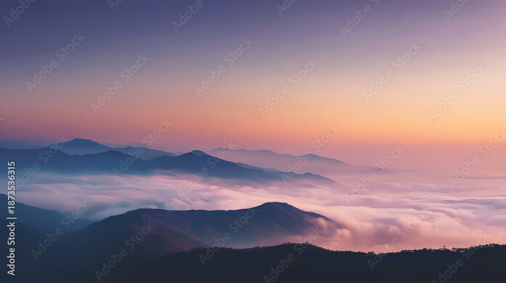 Obraz premium A breathtaking view of mountains shrouded in mist during a colorful sunset, offering a serene and tranquil atmosphere.