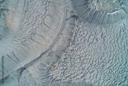 Abstract gray clay texture of industrial wasteland with crater depressions and dry soil bubbles, desolate earth background aerial top down view
