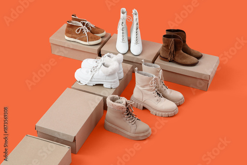 Slika na platnu Winter boots with shoe boxes on orange background