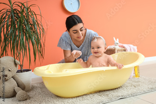 Happy mother bathing her ba...