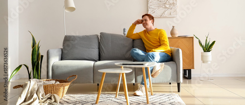 Young man sitting on couch ...