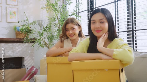 Smiling two young Asian women looking at camera in living room at home