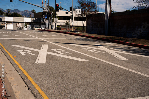 Foto Railroad crossing markings on asphalt road with traffic signals and buildings in