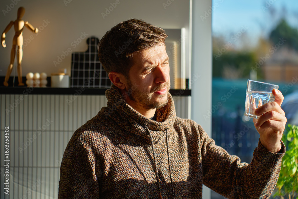 custom made wallpaper toronto digitalAdult man drinking fresh clean water from glass while standing in kitchen near window with sunlight. Person quenching thirst at home. Concept of hydration and healthy lifestyle