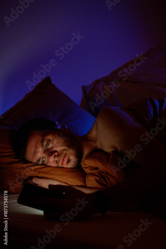 Wallpaper Mural Man lying in bed holding smartphone and looking at screen in night. Concept of insomnia, sleep problems, night phone use and digital addiction Torontodigital.ca