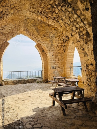 One of the interior halls of St. Hilarion Castle with elegant arched windows opening to sweeping views of the northern coastline of Cyprus, showcasing medieval stone architecture, soft natural light