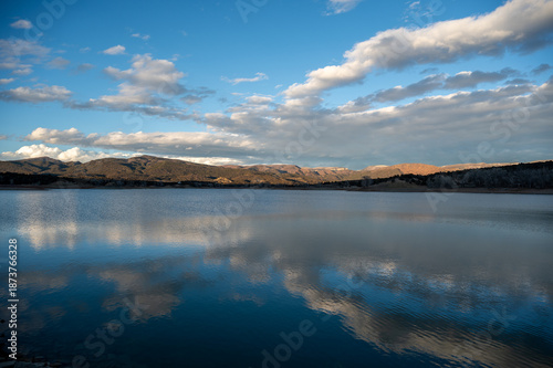 Colorful sunset cloudscape over Grass Valley Reservoir in Harvey Gap State Park, Colorado reflected in lake's calm water.