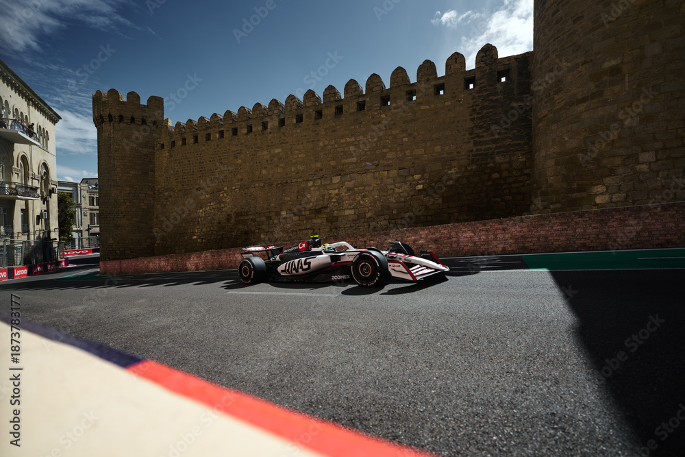 Fototapeta premium BAKU, AZERBAIJAN - SEPTEMBER 20, 2025: A MoneyGram Haas F1 Team car navigates the narrow Turn 8 