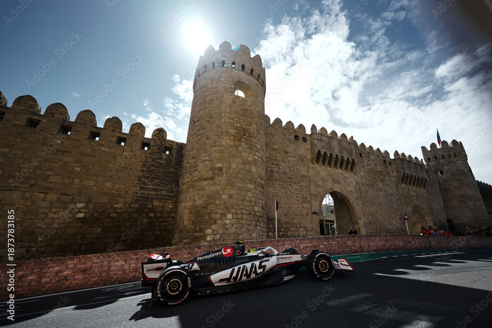 Fototapeta premium BAKU, AZERBAIJAN - SEPTEMBER 20, 2025: A MoneyGram Haas F1 Team car navigates the narrow Turn 8